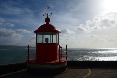 Lighthouse by sea against sky during sunset