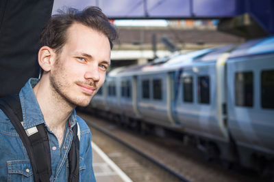 Portrait of a young caucasian man waiting for train on platform at a london train station 