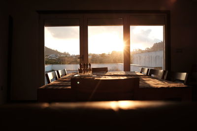 Chairs and table by window at sunset