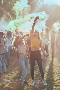 Happy friends playing with powder paint while standing outdoors