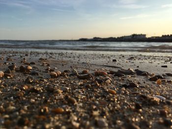 Surface level of beach against sky during sunset