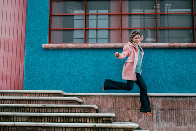 Full length of woman in mid-air jumping over steps by house