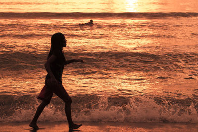 Side view of woman on beach during sunset