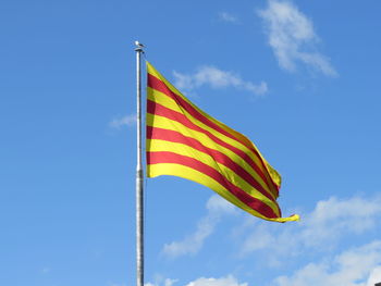 Low angle view of flag against blue sky