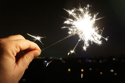 Hand holding firework display at night