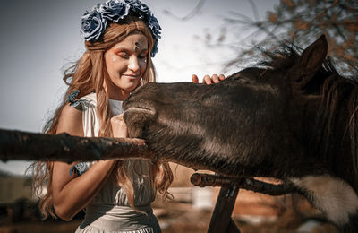 Woman wearing traditional clothes standing with horse outdoors