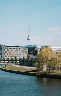 Buildings by river against clear sky