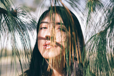 Close-up portrait of young woman with palm tree