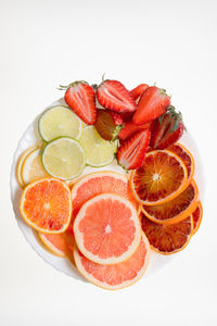 Slices of fresh fruit on plate on white background
