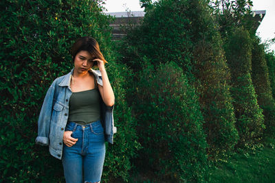 Young woman using mobile phone while standing on tree