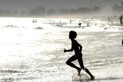 Silhouette of boy running at sea shore