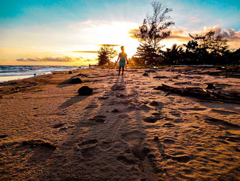 Man on beach against sky during sunset