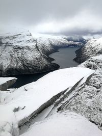 Frozen lake by snowcapped mountain against sky