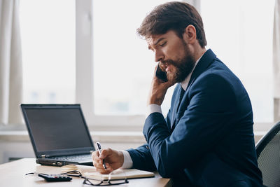 Young man using mobile phone while sitting on table