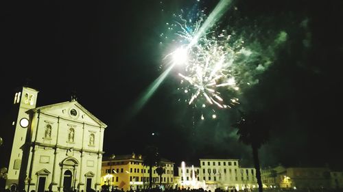 Low angle view of firework display in city against sky at night