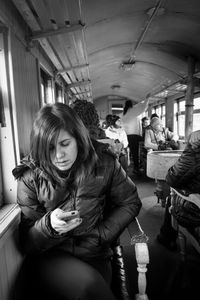 Woman using mobile phone while sitting in train