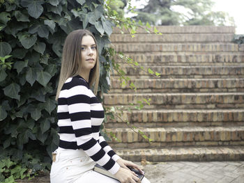 Portrait of young woman standing against plants