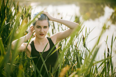 Portrait of young woman amidst cattails on field