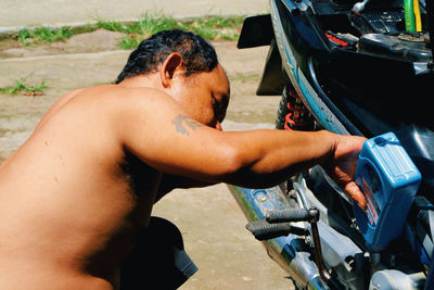 Side view of shirtless man lying on motorcycle