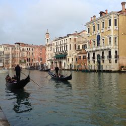 People on boat in canal against buildings