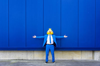 Full length of man standing against blue wall