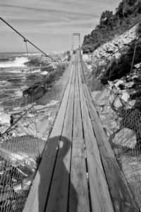 Footbridge over sea against sky