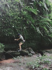 Full length of woman standing on rock in forest