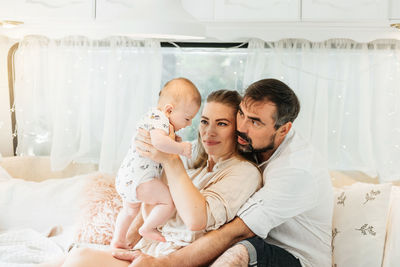 Family with baby on the bed in trailer in the morning. newborn child traveling in camper with