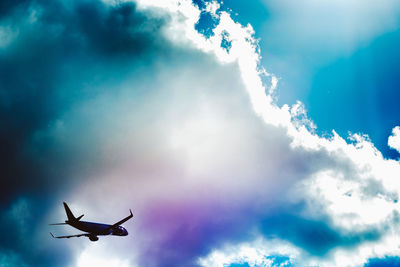 Low angle view of airplane flying in cloudy sky