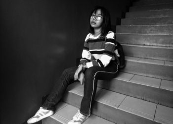 Young woman looking down while sitting on staircase