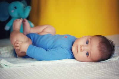 Portrait of cute baby lying on bed at home