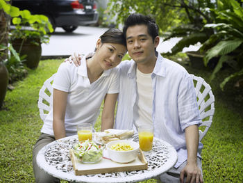 Portrait of smiling couple embracing during breakfast at yard