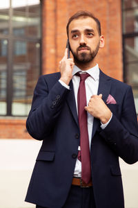 Young businessman talking on mobile phone on footpath