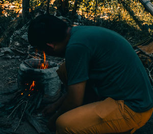 Rear view of man and woman sitting on log in forest