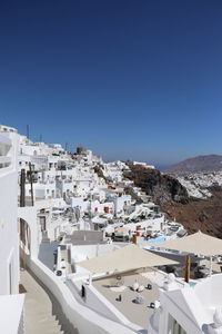 Panoramic view of buildings in town against clear blue sky