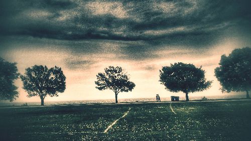 Road passing through field against cloudy sky