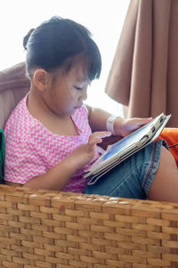 Little girl with digital tablet on the sofa.