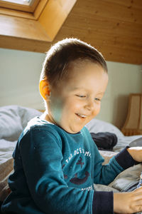 Portrait of cute boy looking away while sitting on sofa at home