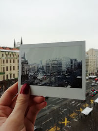 Cropped image of woman holding cityscape against sky
