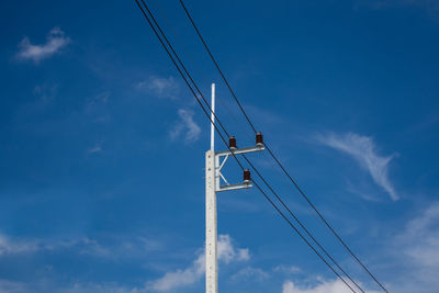 Low angle view of telephone pole against blue sky