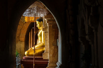 Buddha statue in temple seen through doorway