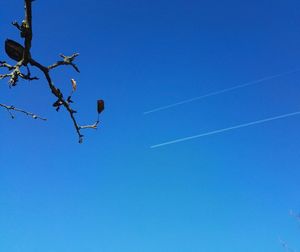 Low angle view of vapor trail against clear blue sky