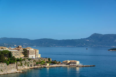 Sea by buildings against clear blue sky