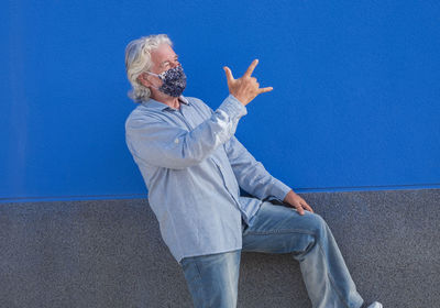 Midsection of man standing by wall against blue sky