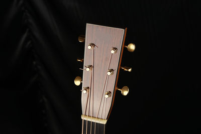 Cropped image of acoustic guitar on bed