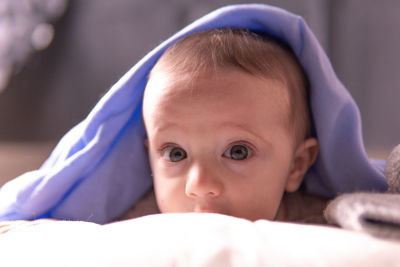 Close-up portrait of cute baby lying down on bed