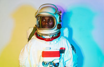 Man wearing space suit standing against colored background