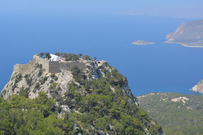 Scenic view of sea by mountains against clear blue sky