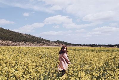 Portrait of woman standing amidst flowering plants against sky