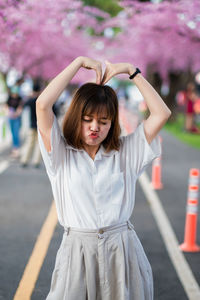 Portrait of young woman standing against blurred background